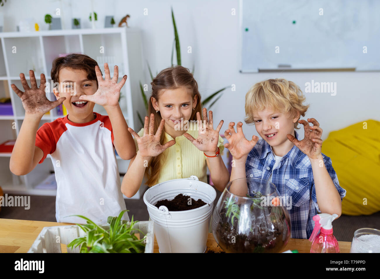 Mostra le mani sporche. Funny gli studenti mostrando loro le mani sporche dopo piante di incapsulazione a lezione di ecologia insieme Foto Stock