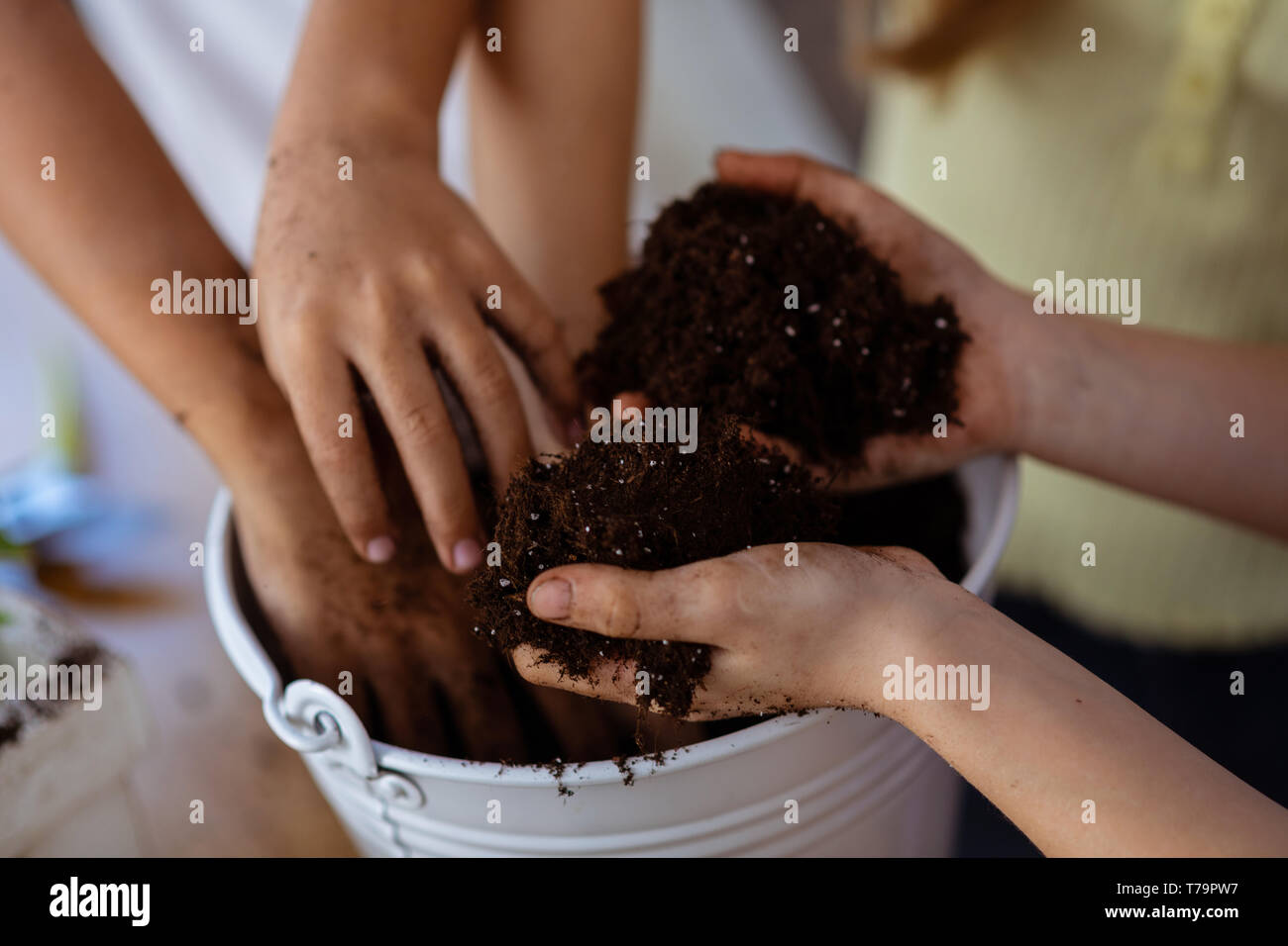 Le mani e il suolo. Close up di bambini e insegnanti di incapsulazione di contenimento terreno alla lezione di ecologia a scuola Foto Stock