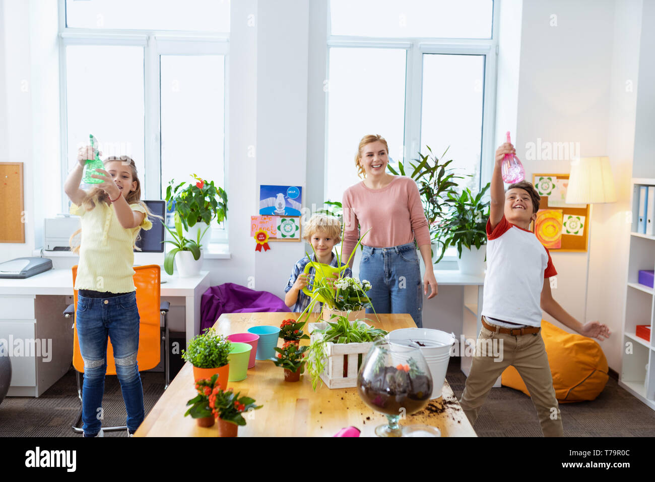 Diffusori e pot. Gli alunni il contenimento dell'acqua diffusori e annaffiatura pentola a lezione di ecologia mentre sta in piedi vicino al maestro Foto Stock