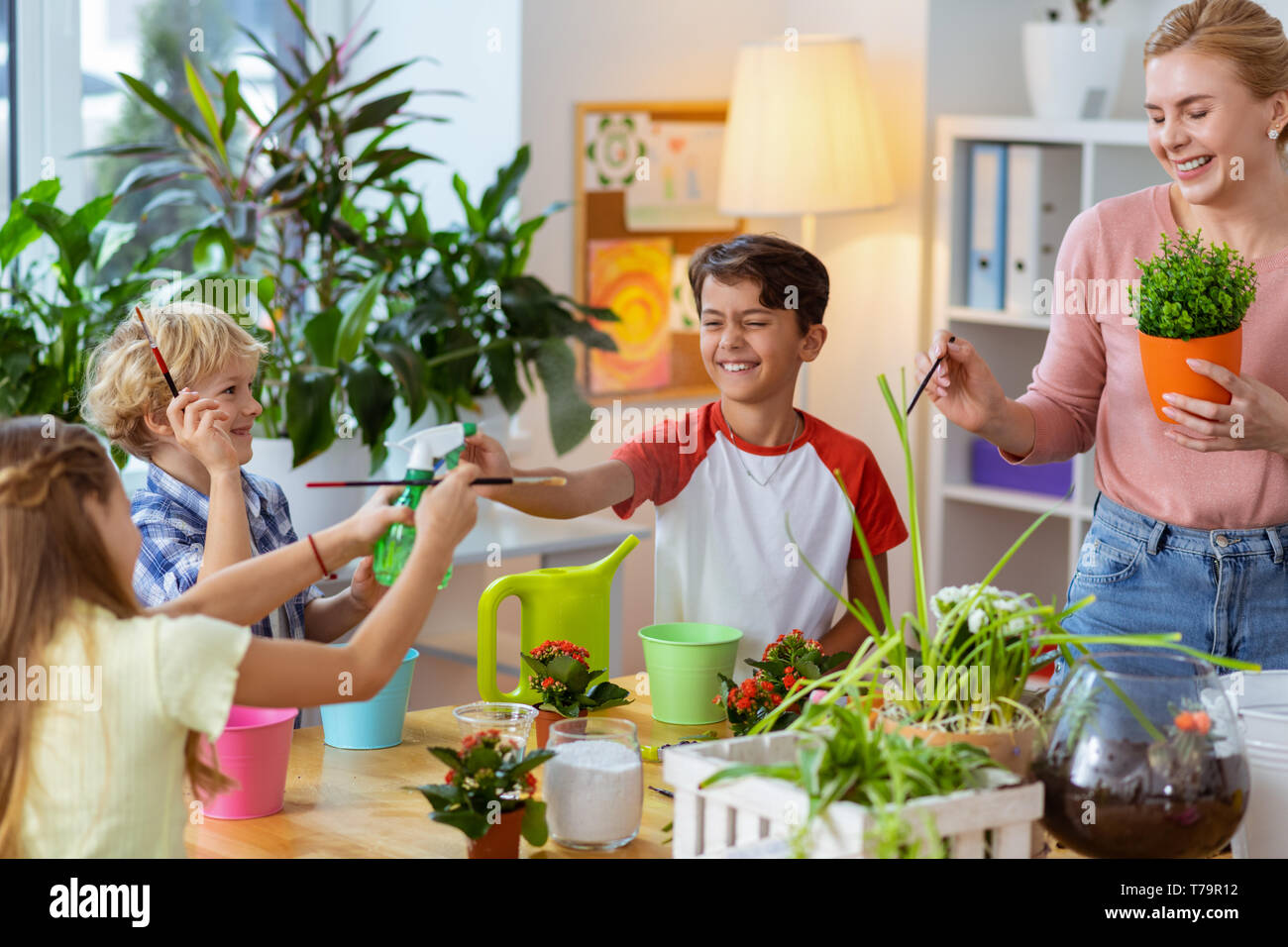 A ridere prima della verniciatura. Gli alunni e gli insegnanti di ridere mentre le spazzole di contenimento prima della verniciatura dei vasi da fiori insieme Foto Stock