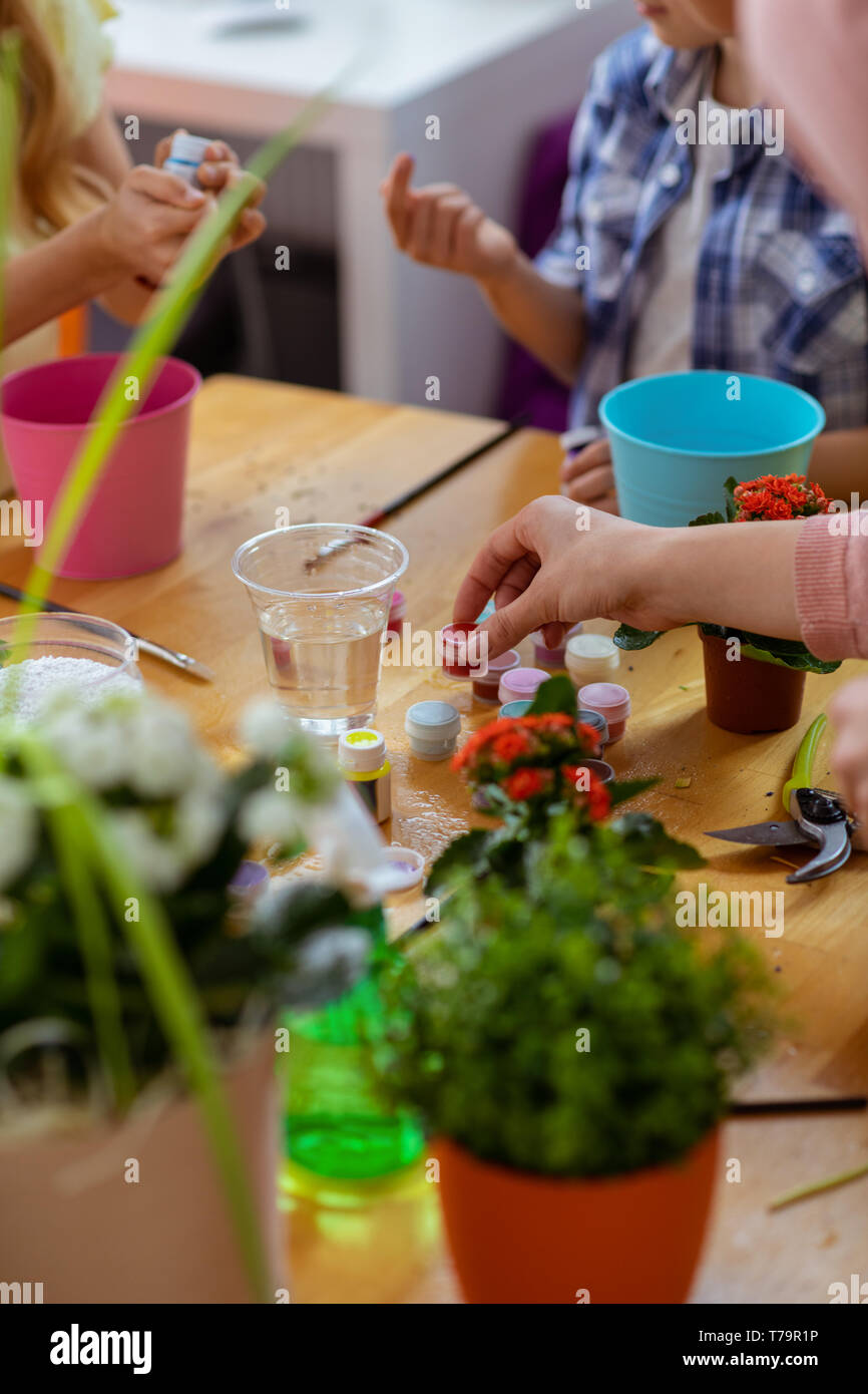 Tenendo guazzo. Gli alunni tenendo gouache colorate mentre la colorazione dei vasi da fiori a lezione di ecologia insieme Foto Stock