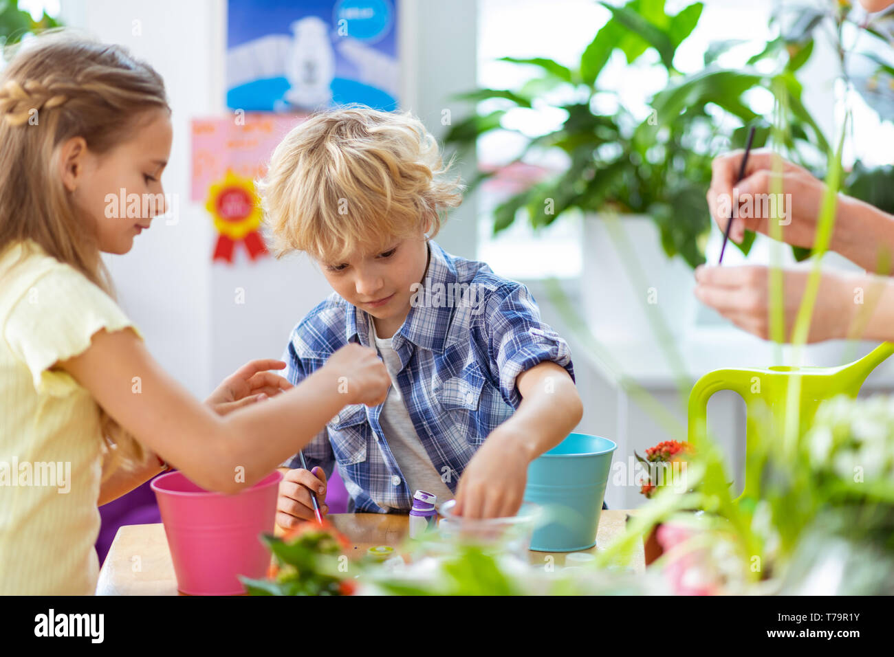 La colorazione dei vasi da fiori. Scolaro e schoolgirl la colorazione dei vasi da fiori con il loro insegnante a lezione di ecologia Foto Stock