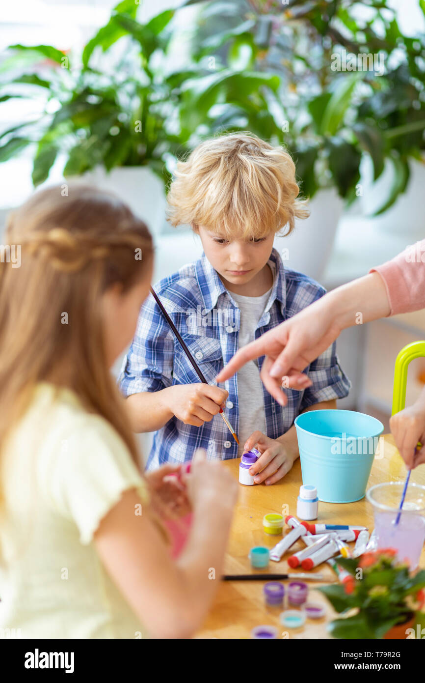 Ragazzo con la spazzola. Bionda boy tenendo la verniciatura a pennello la lezione a scuola mentre in piedi vicino a ragazza Foto Stock