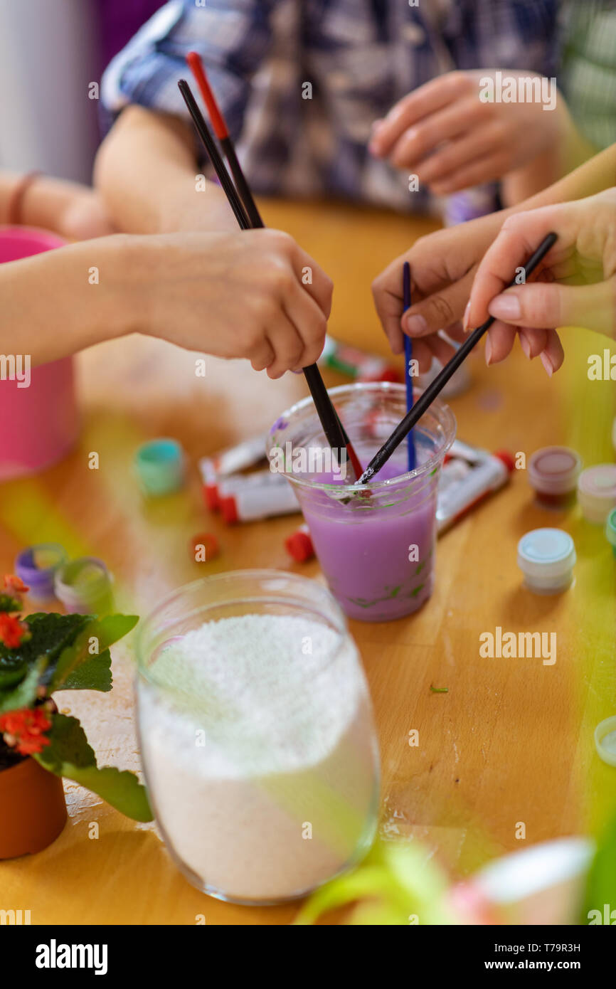 Gouache viola. Gli alunni e gli insegnanti di mettere la pittura Pennelli in viola gouache mentre la colorazione insieme Foto Stock
