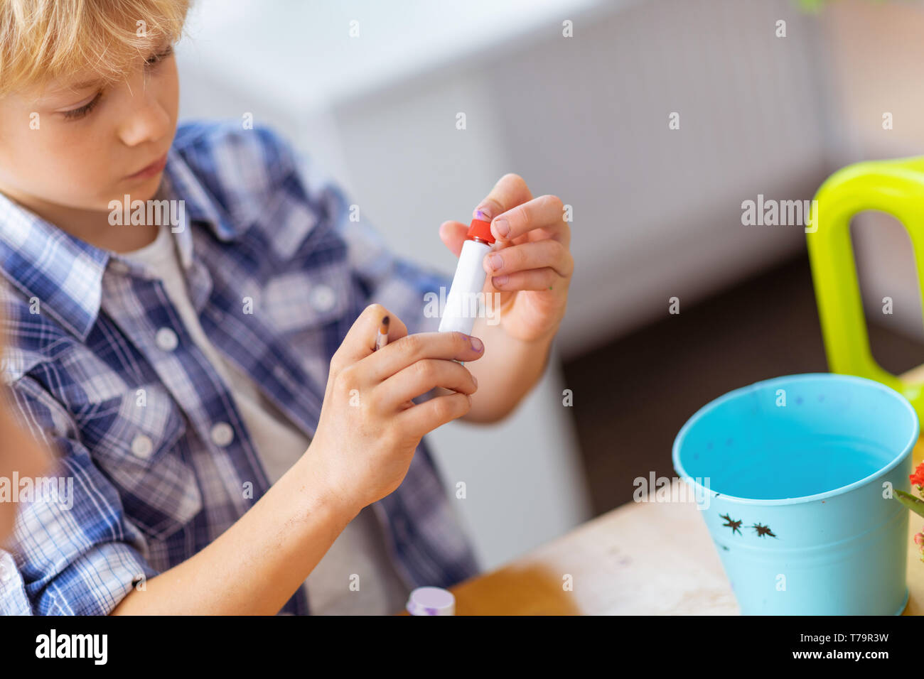 Gouache apertura tubo. Biondo e schoolboy gouache apertura tubo prima di pittura presso la lezione Foto Stock