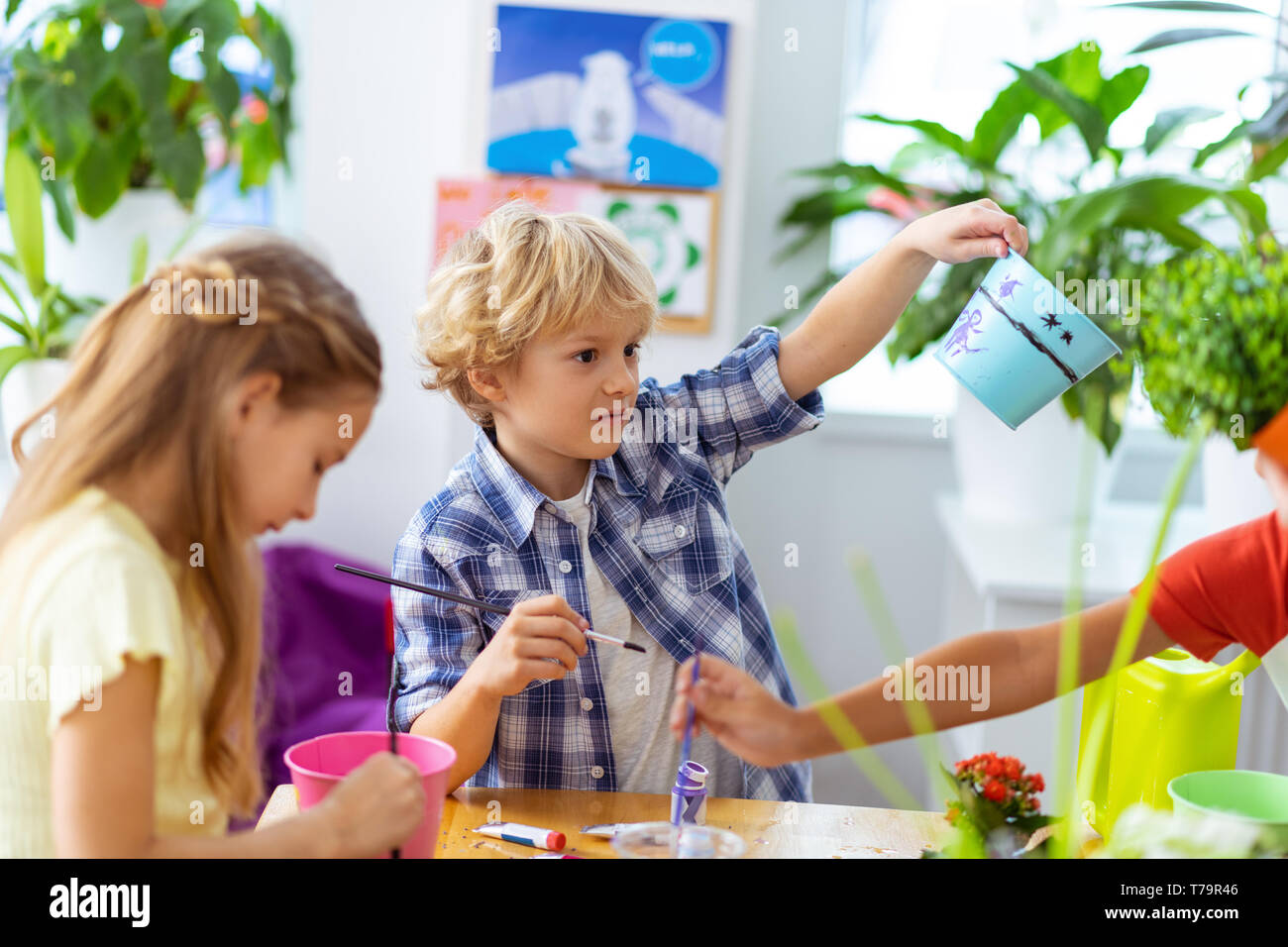 Soddisfatto boy. Bionda boy sentirsi soddisfatto dopo la verniciatura vaso con i compagni di classe a lezione di ecologia Foto Stock