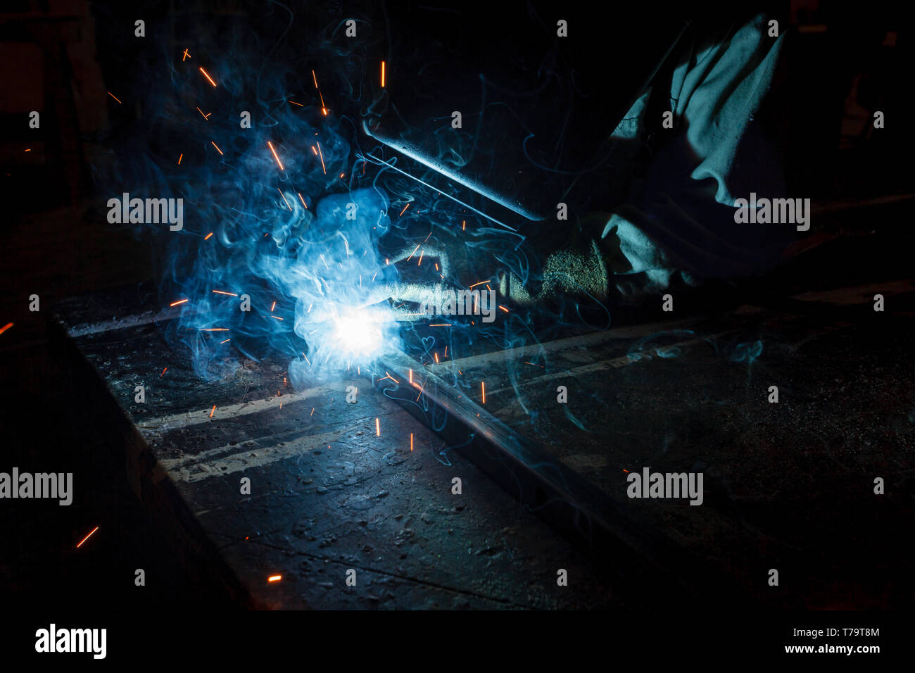 Primo piano della saldatura sul sito di costruzione di notte con doccia di scintille e blu arca di elettricità Foto Stock