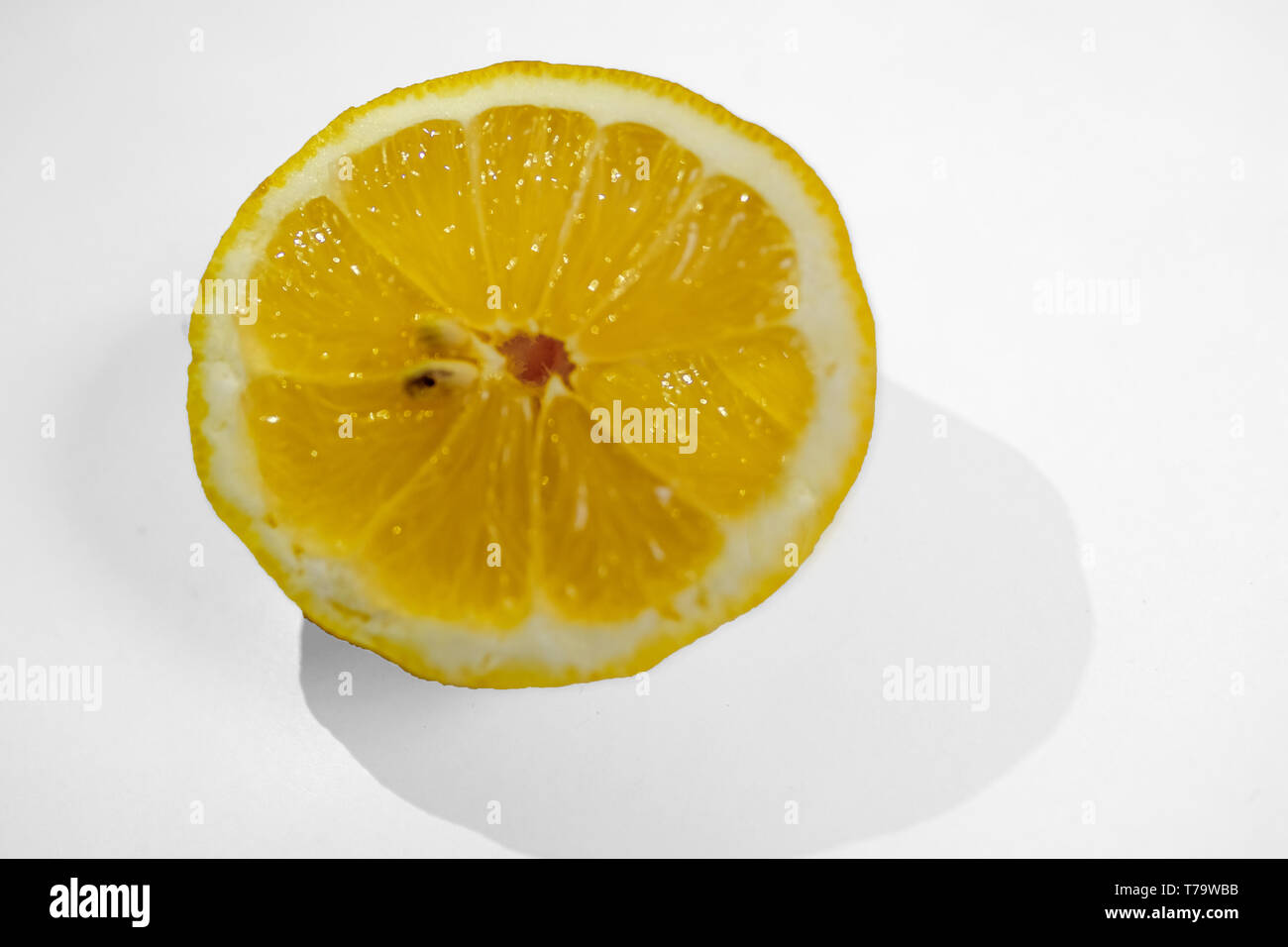 La metà di un limone giallo con due pip su uno sfondo bianco con un shaddow del limone. Foto Stock