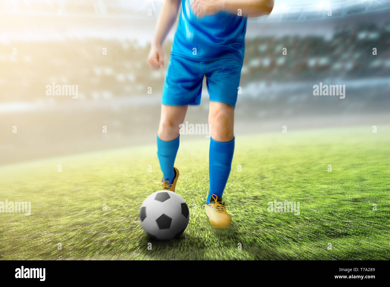 Giocatore di football uomo calciare la palla sul campo di calcio a Stadium Foto Stock