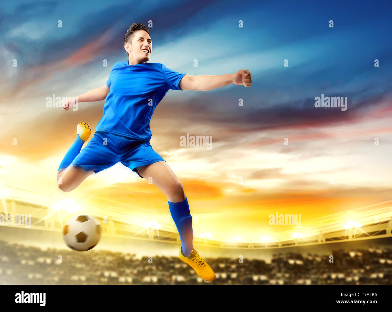 Asian giocatore di football uomo a saltare e calciare la palla in aria sul campo di calcio a Stadium Foto Stock