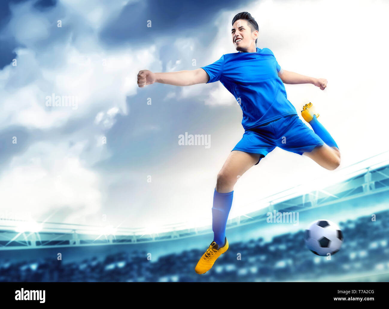 Asian giocatore di football uomo a saltare e calciare la palla in aria sul campo di calcio a Stadium Foto Stock