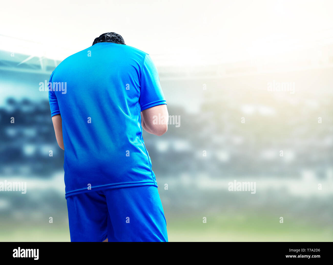 Vista posteriore di asian giocatore di football uomo festeggiare il suo obiettivo in piedi sul campo di calcio a Stadium Foto Stock