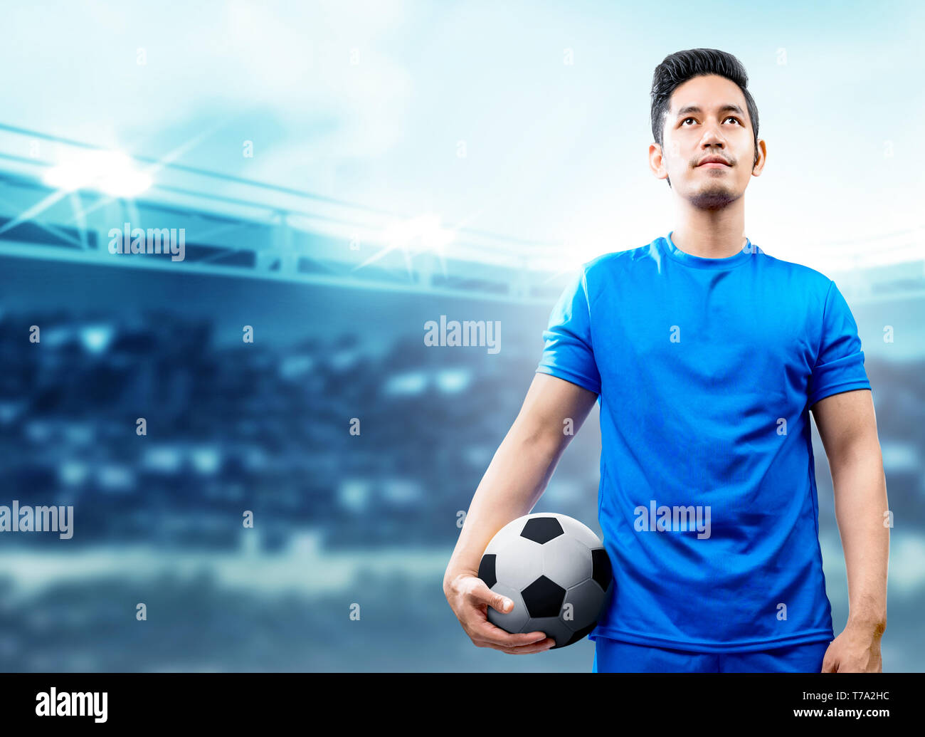 Asian giocatore di football uomo in maglia blu tenendo la palla sul campo di calcio a Stadium Foto Stock