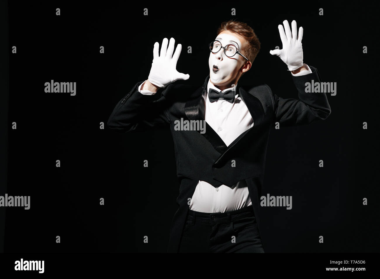 Ritratto di mime uomo tiene le mani su un muro invisibile su sfondo nero Foto Stock