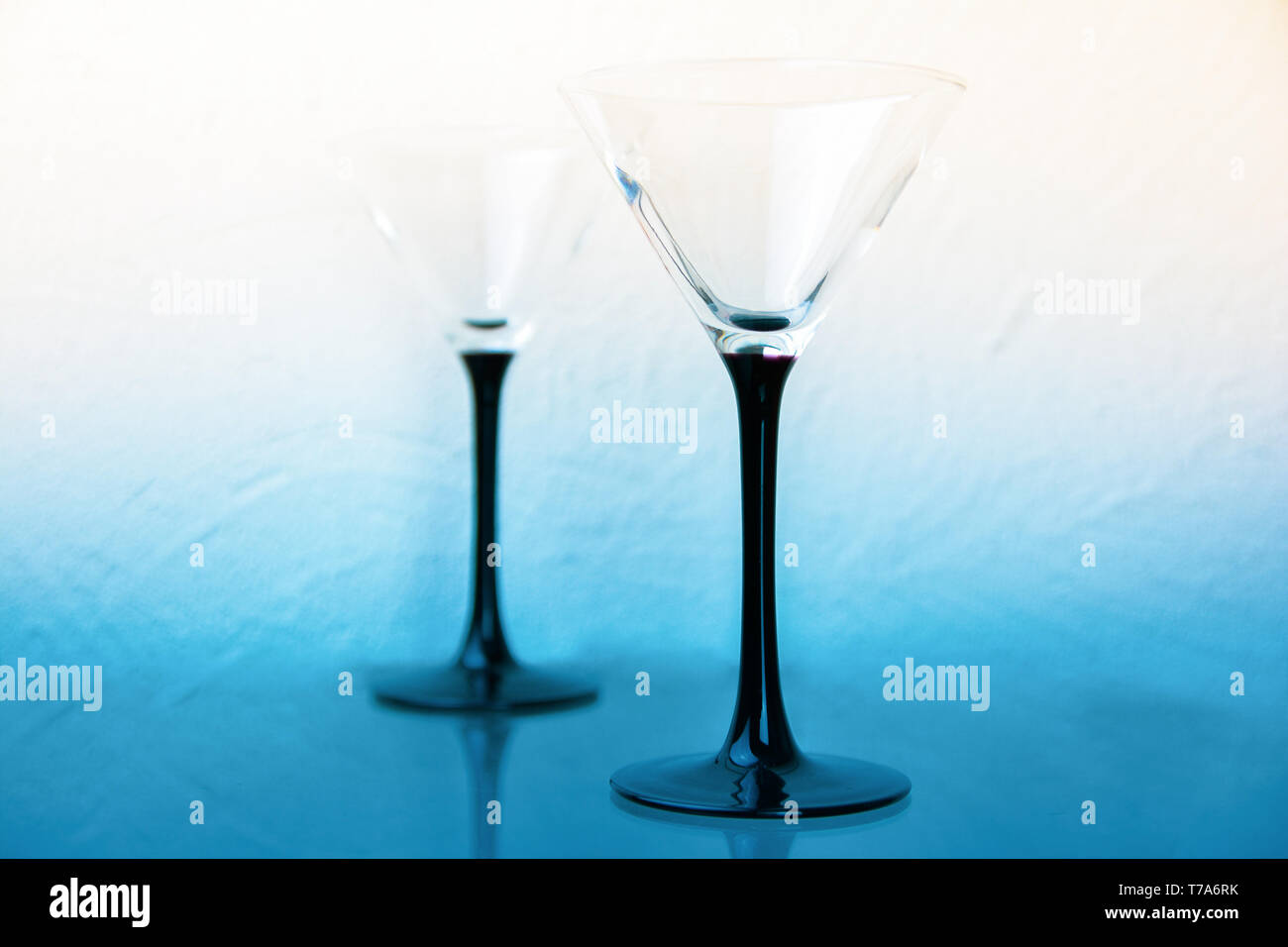 Due bicchieri da martini su gambe nero su bianco-blu di sfondo. Foto Stock