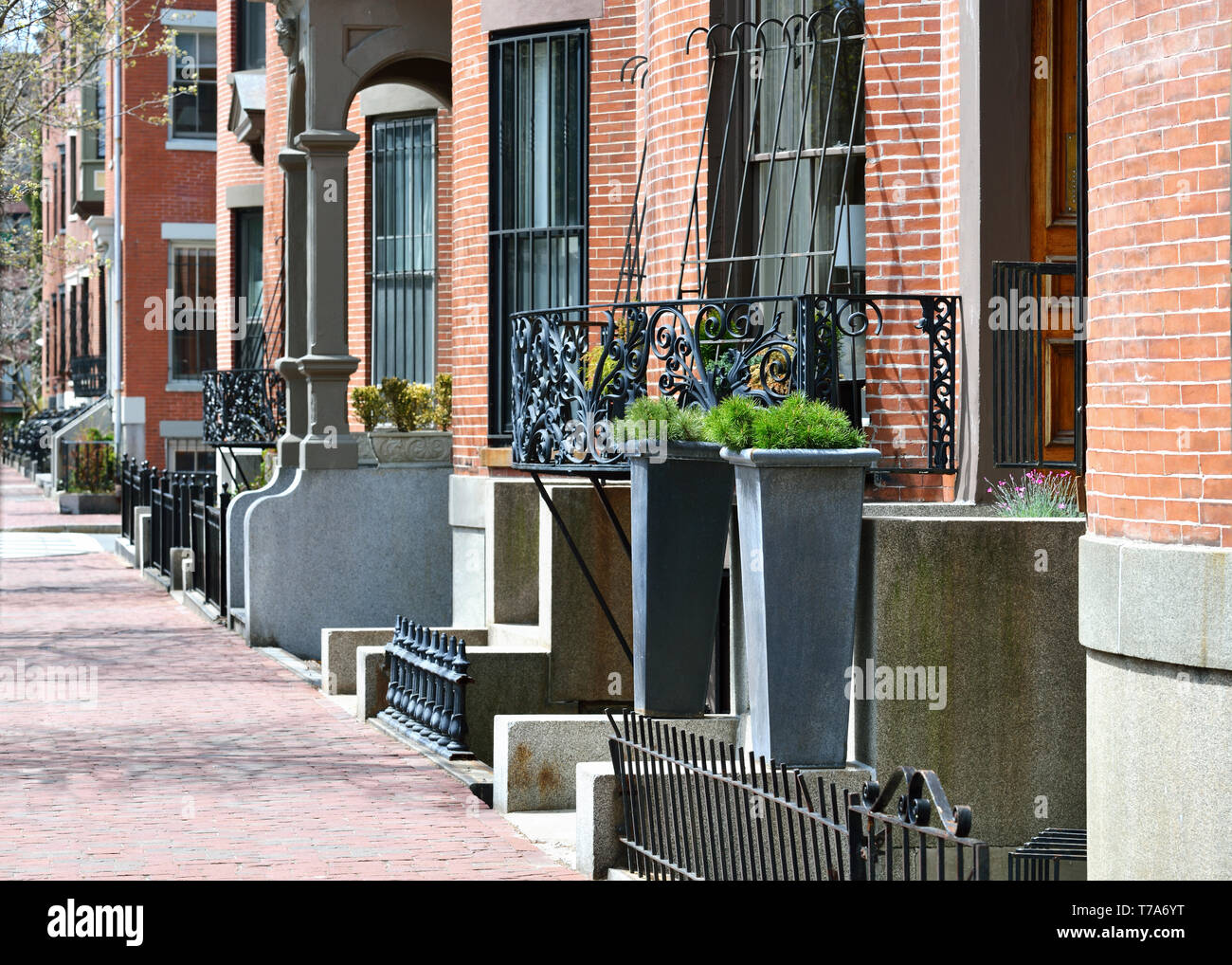 Boston South End per architettura. Mattone rosso marciapiede e fila facciate di case, ghisa recinzioni, griglie e balconi, entrata in pietra passi, giardino urna, sty Foto Stock