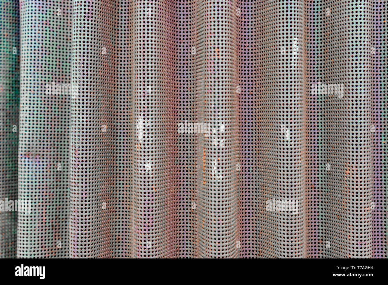Foto di sfondo di curva schermo metallico utilizzato come uno sfiato su vecchie attrezzature agricole. Sbiadita della vernice verde con riflessi aranciati dalla ruggine. Buchi nella maglia. Foto Stock