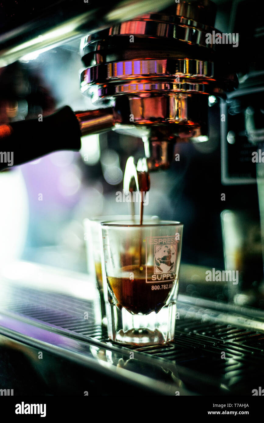 La preparazione di caffè espresso close up dettaglio con gli occhiali e la caffetteria moderna macchina Foto Stock