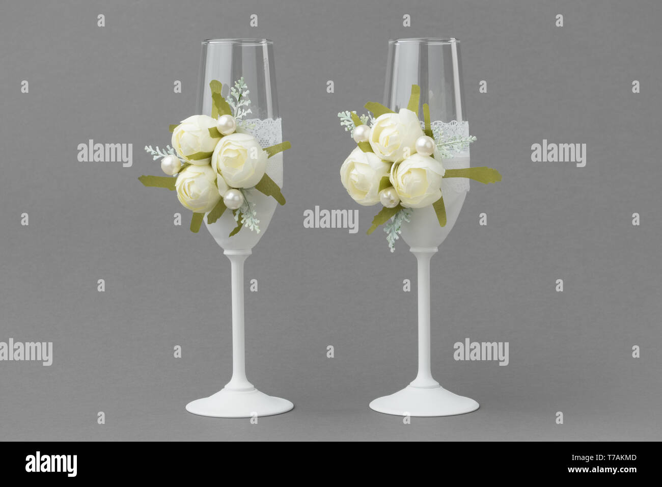 Matrimonio di due bicchieri di vino decorate con pizzo e rose bianche su sfondo grigio. Foto Stock