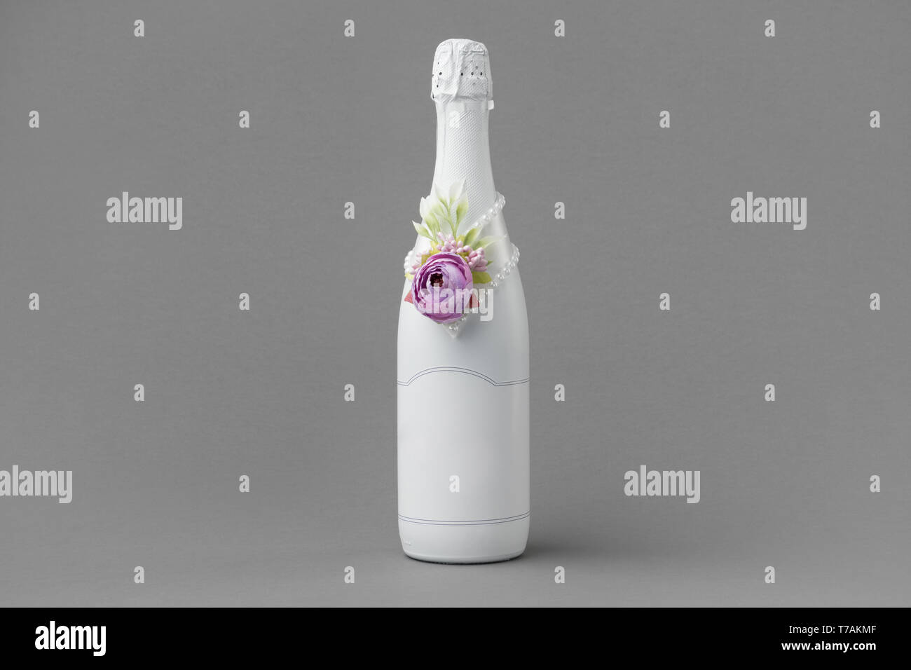 Nozze bottiglia di champagne con etichetta vuota. Bottiglia decorata con rose, perle e nastro. Copia spazio per il testo. Foto Stock