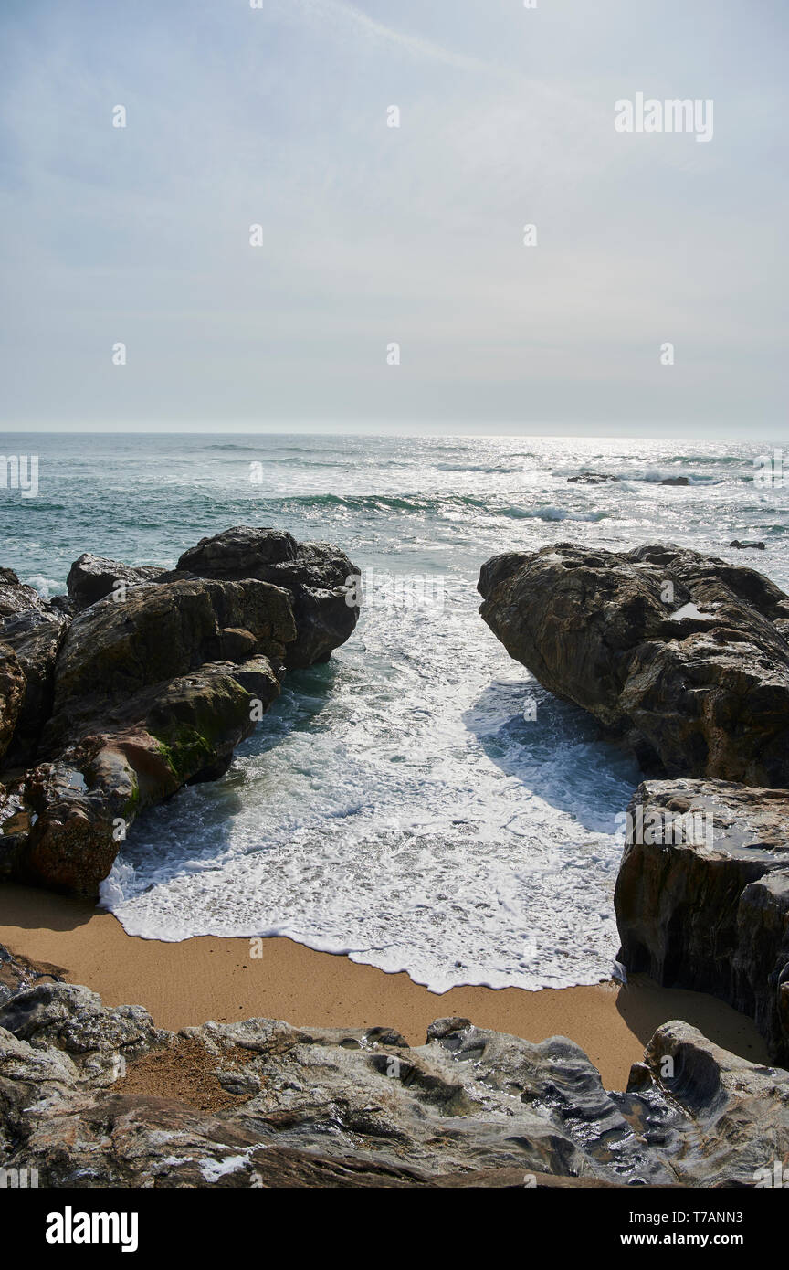 Wave è venuto tra due rocce e coprire la sabbia della baia Foto Stock