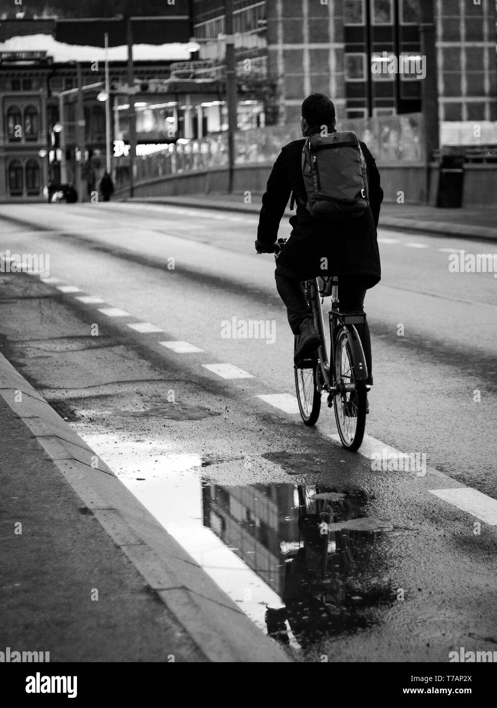 Uomo in sella alla sua moto nella città. Acqua pit edifici riflettente Foto Stock