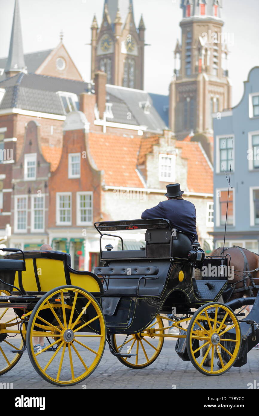 DELFT, Paesi Bassi - 22 Aprile 2019: Close-up su il cocchiere di una carrozza a cavallo, tradizionalmente condita e con facciate colorate in background Foto Stock