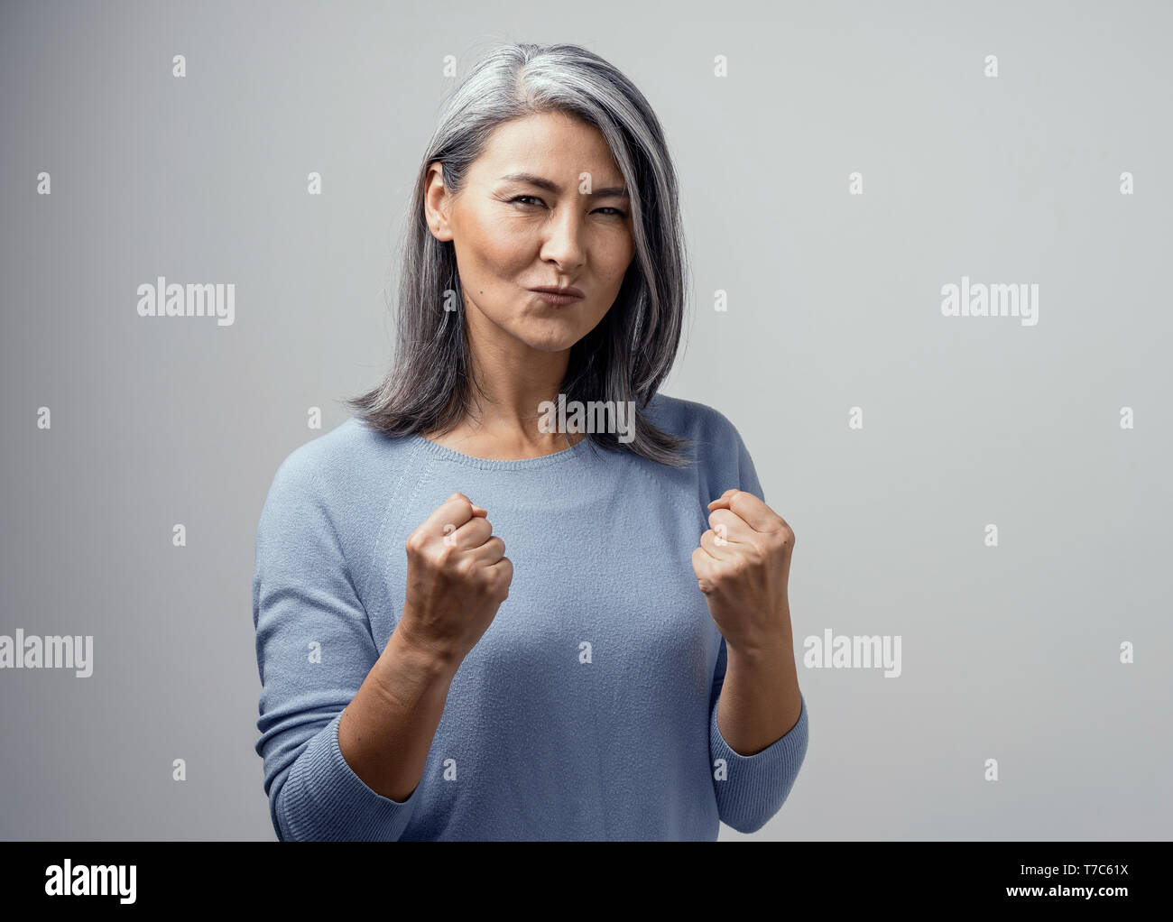 Felice coppia asiatica di modello femminile sorride felicemente. Essa celebra la vittoria e tiene i pugni nella soddisfazione. Foto di mano in Studio su sfondo bianco Foto Stock