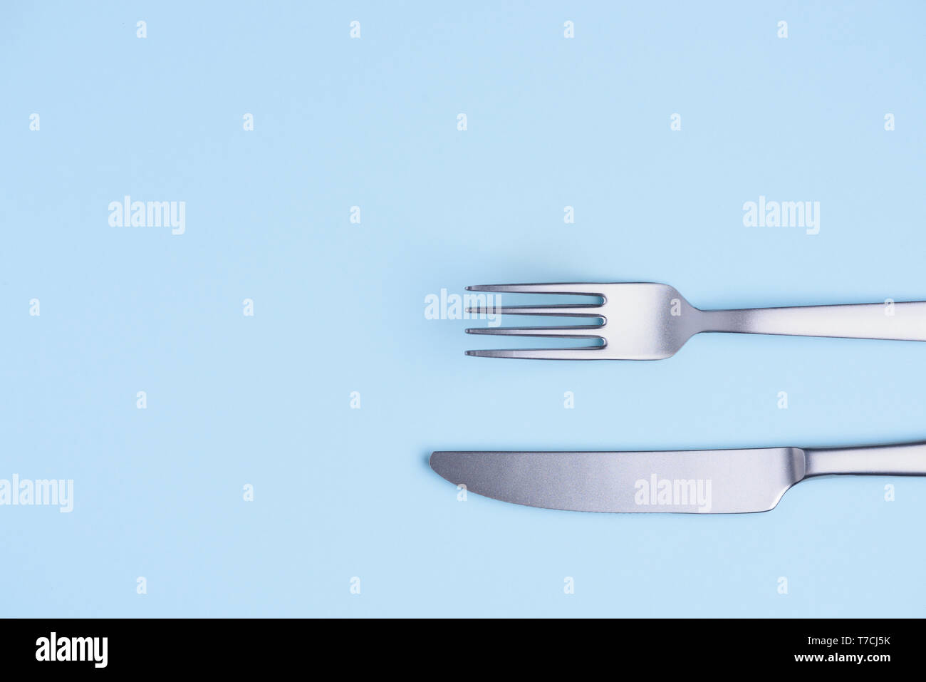 Coltello e forchetta blu su sfondo pastello flay lay Foto Stock