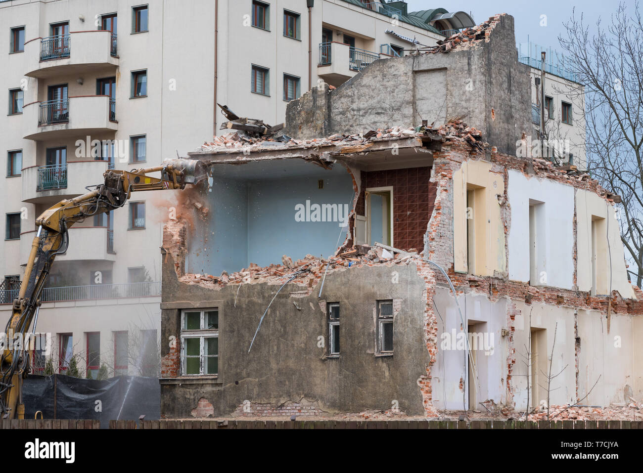 Residenziale di vecchio edificio di tre piani demolizione con escavatore Foto Stock