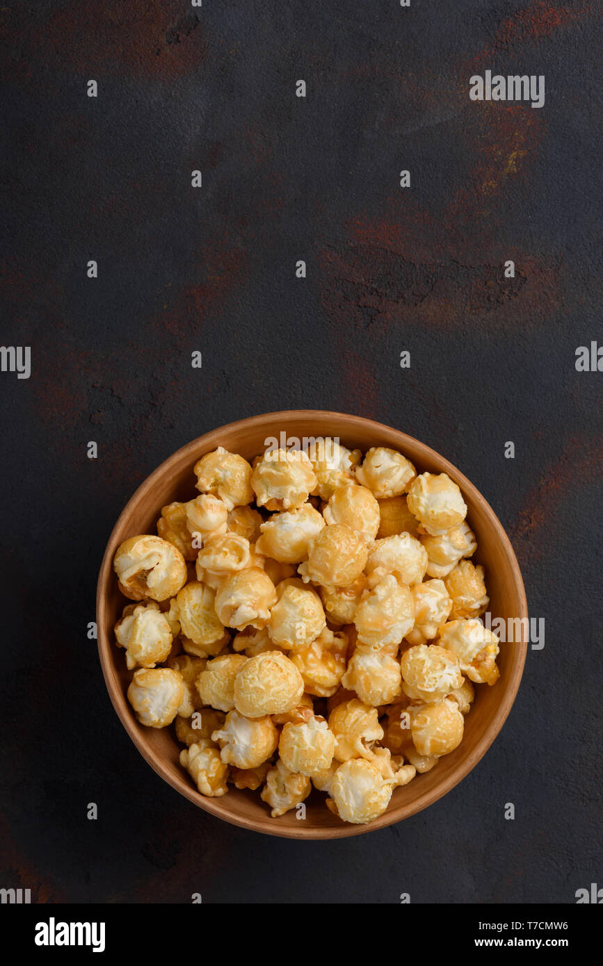 Caramello popcorn nel recipiente verticale sulla tabella scuro con spazio di copia Foto Stock