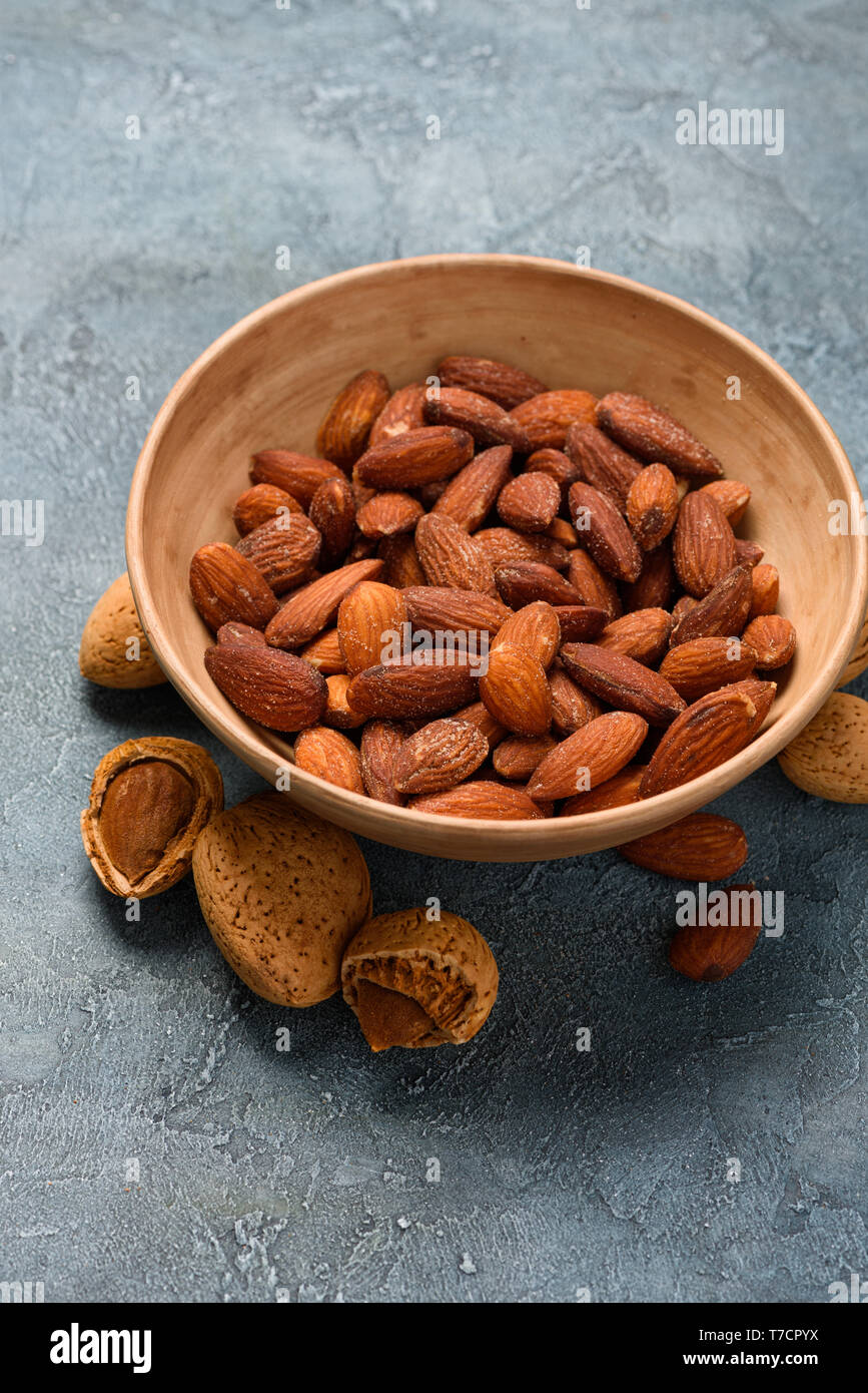 Fritti di mandorla salata dadi in una ciotola di ceramica su sfondo rustico Foto Stock