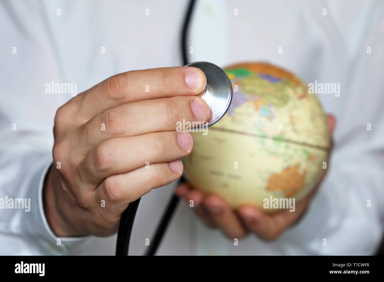 Medico con lo stetoscopio e il mondo nella sua mano. Rete medica e sanitaria nel sud-est asiatico, India e Cina, il concetto di medicina del mondo, epidemia Foto Stock
