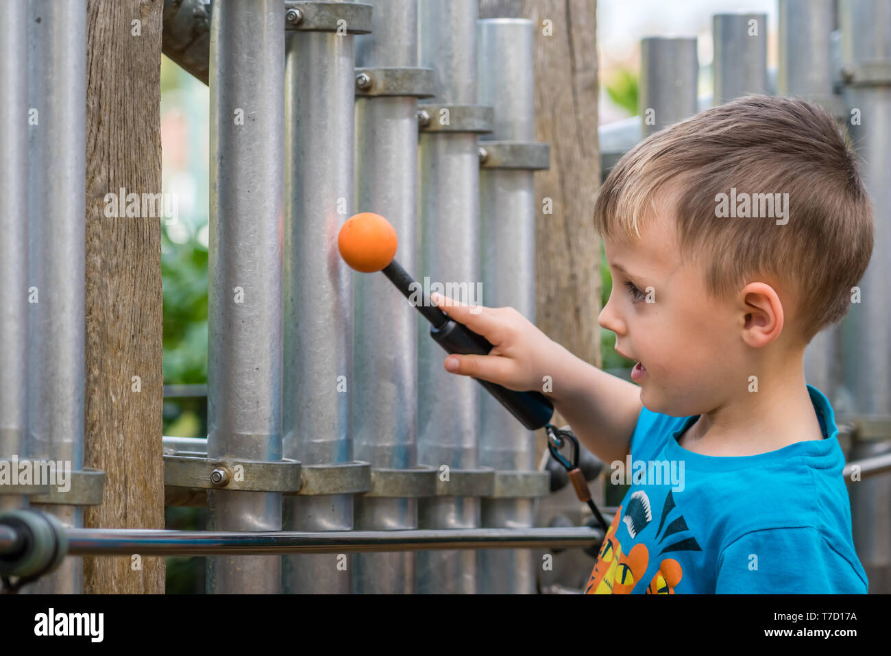 Grazioso piccolo ragazzo caucasico giocando toy Tubular Bells nel parco giochi pubblico Foto Stock