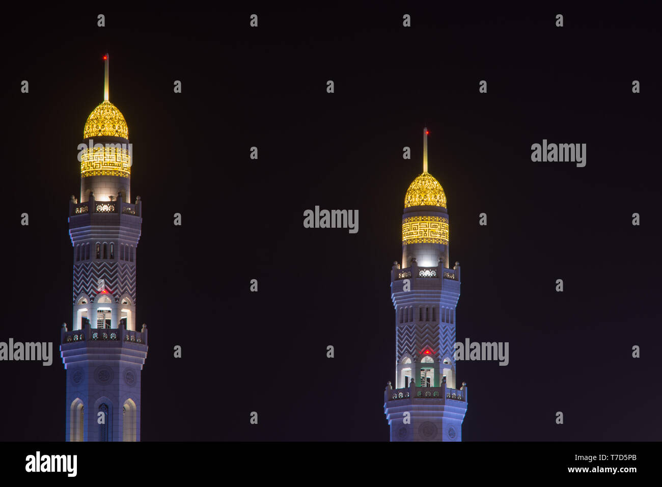 Al Ameen città minareti della Moschea incandescente di notte porpora e giallo in Muscat Oman. Foto Stock