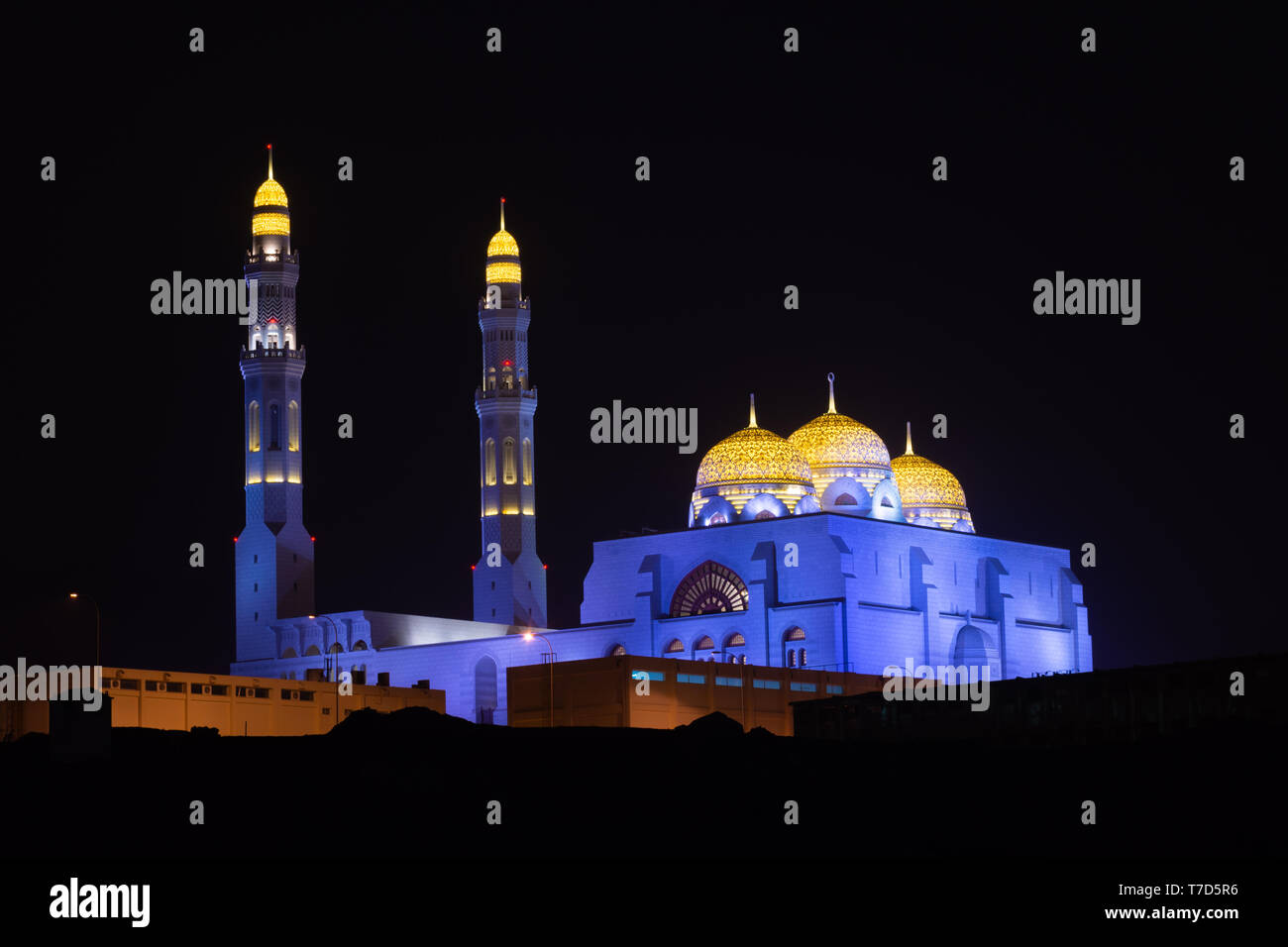 Al Ameen moschea della città incandescente di notte porpora e giallo in Muscat Oman. Foto Stock