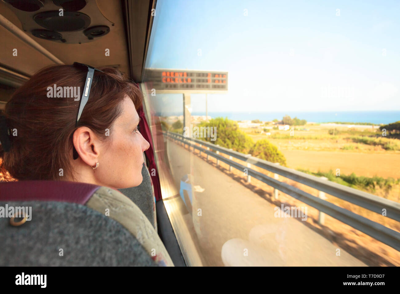 Donna sul sedile del passeggero del bus. Lei guarda fuori dalla finestra, al di fuori della finestra è un bellissimo paesaggio con la riva del mare. Foto Stock
