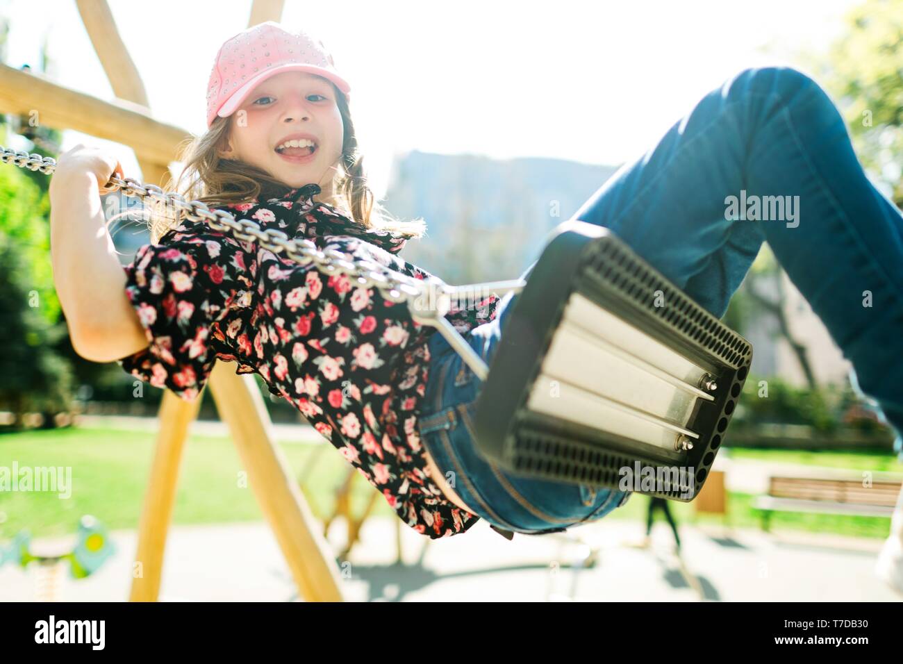 Bambino sorridente nel cappello rosa basculante in parco giochi - giornata di sole e spensierata infanzia Foto Stock