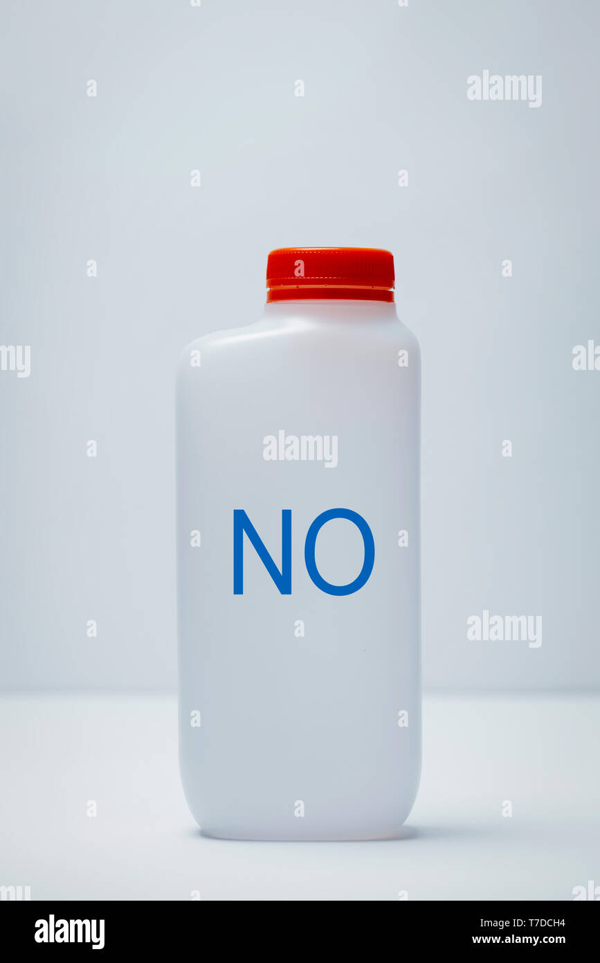Primo piano di una bottiglia di plastica con la parola no scritto in esso, e un cappuccio rosso, su uno sfondo bianco, con un po' di spazio vuoto sulla parte superiore Foto Stock