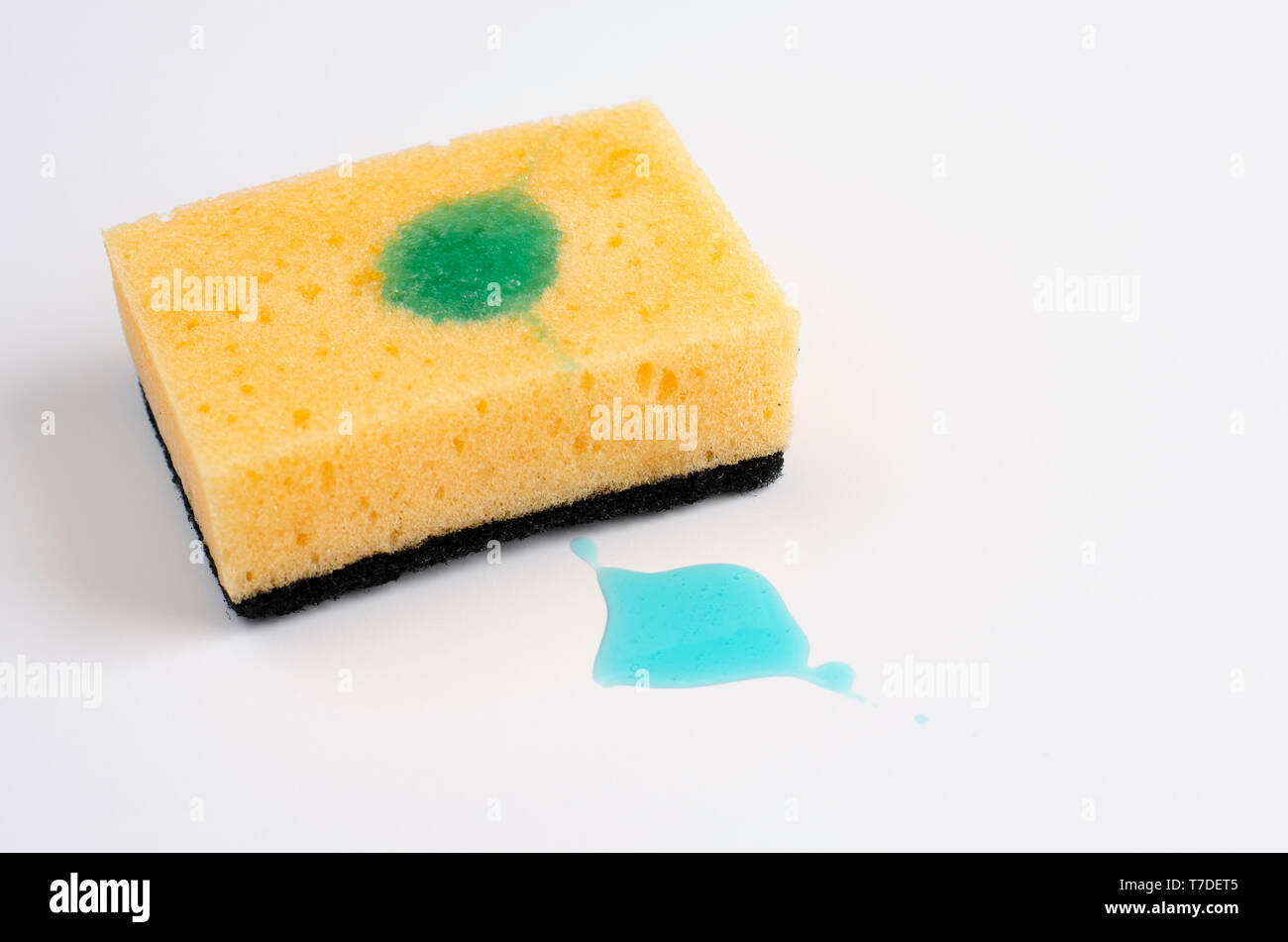 Giallo spugna insaponata con detergente su sfondo bianco. Copia dello spazio. Foto Stock