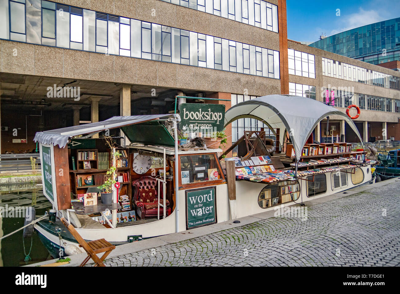 Una libreria galleggiante su una stretta barca ormeggiata sul sentiero di traino del braccio di Paddington del Grand Union Canal, Paddington Basin London, UK Foto Stock
