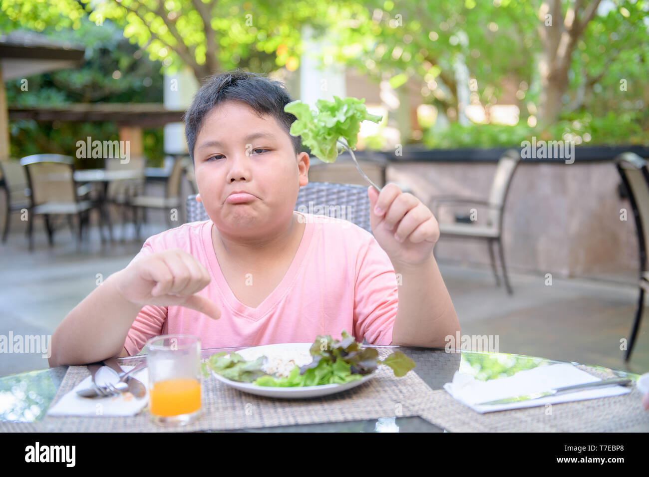Obesi Fat Boy con espressione di disgusto contro le verdure in insalata, rifiutando il concetto di cibo Foto Stock