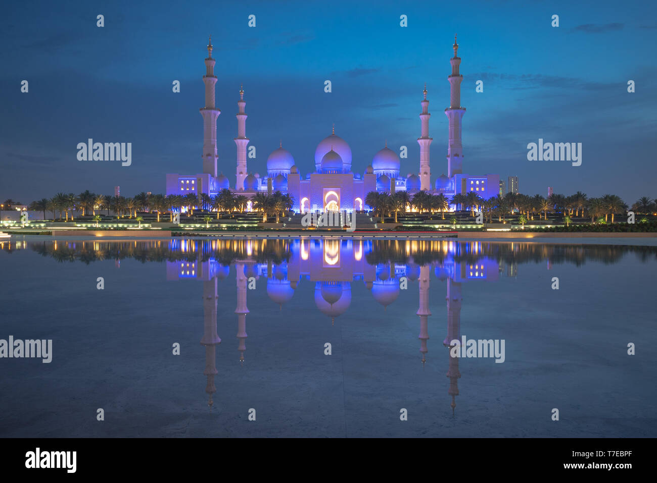 Formato rettangolare di un ampio angolo di visione della Grande Moschea di Abu Dhabi di notte con la riflessione su un acqua, Regno emirato Arabo Foto Stock