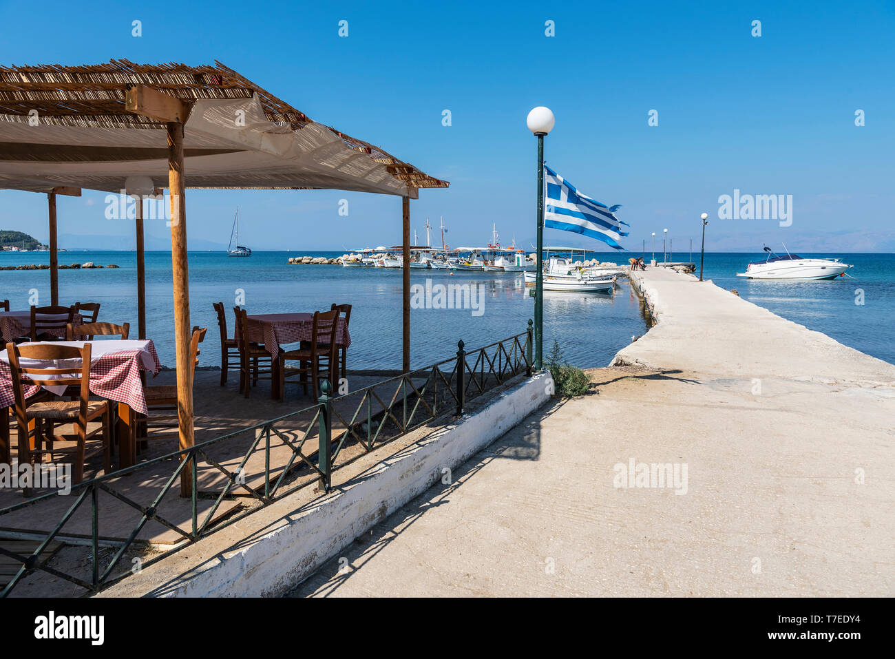 Taverna, ristorante, porta bandiera nazionale, imbarcadero, Kaliviotis, Lefkimmi, isola di Corfu, Isole Ionie, Mare mediterraneo, Grecia Foto Stock