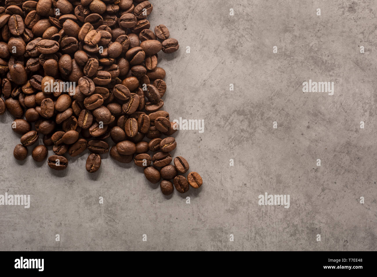 Chicchi di caffè tostati su sfondo di cemento visto da sopra. Foto Stock