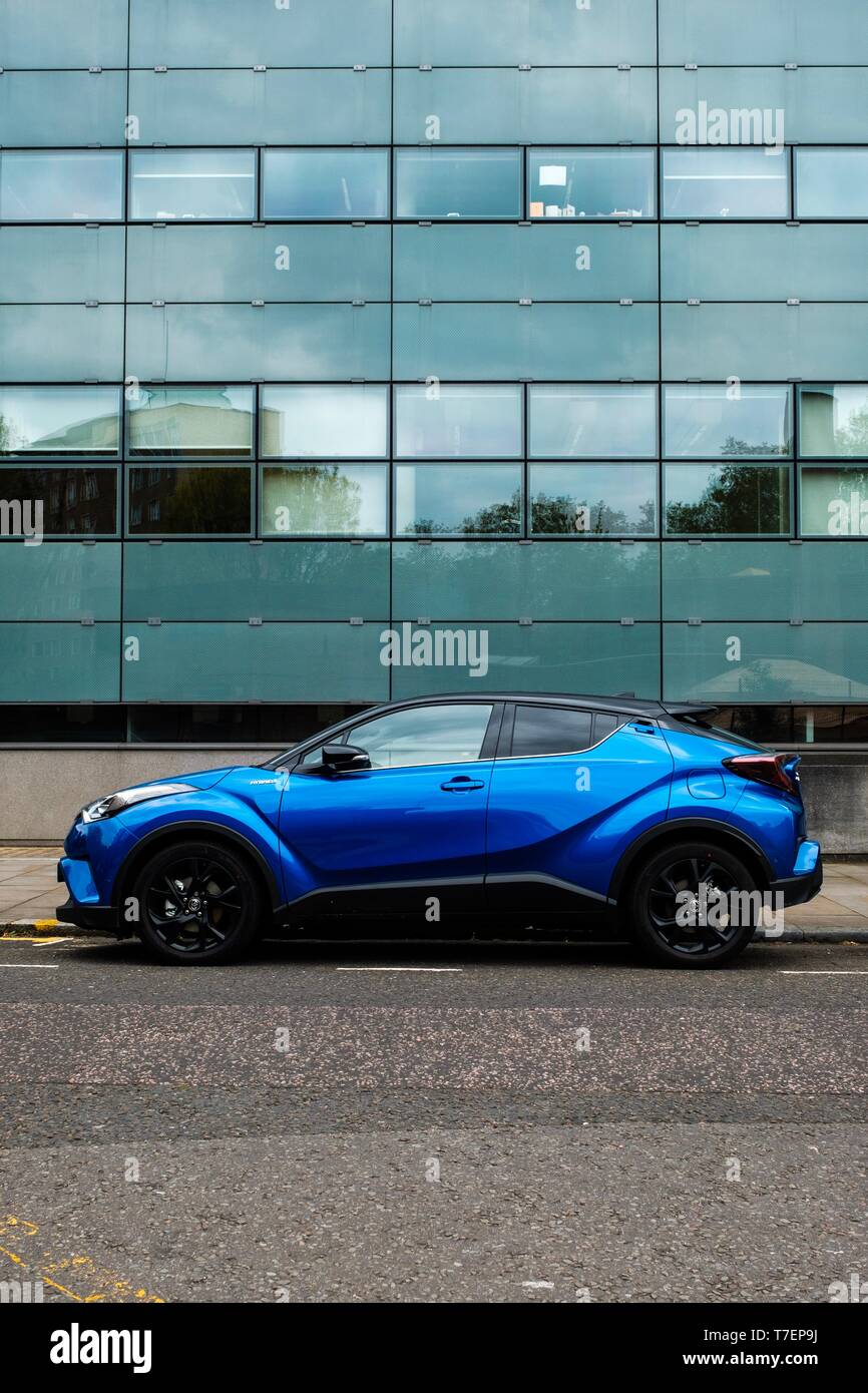 Blue hybrid veicolo parcheggiato in da del vetro frontale edificio per uffici, a nord di Londra Foto Stock