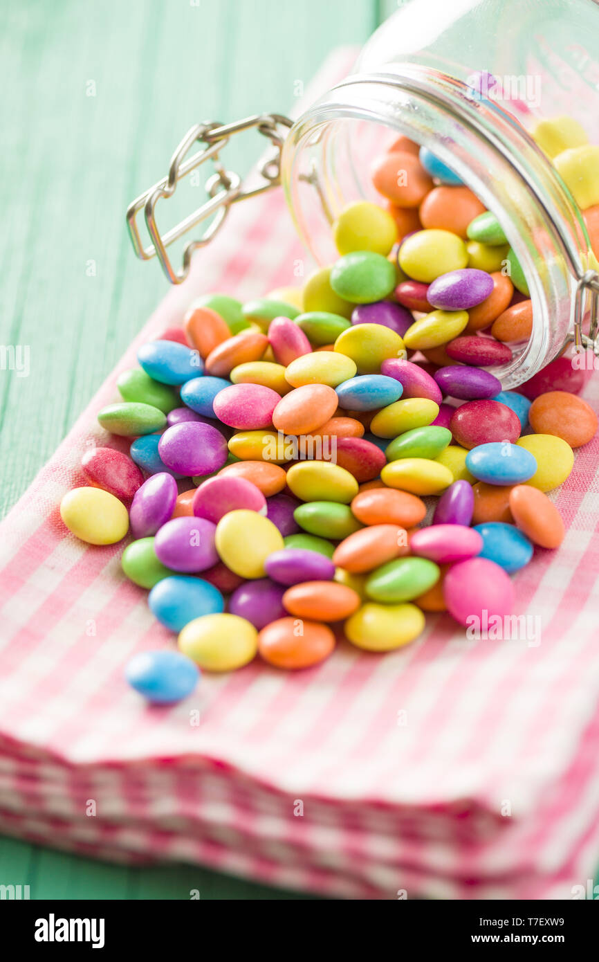 Cioccolato colorato candy pillole sul tovagliolo a scacchi. Foto Stock