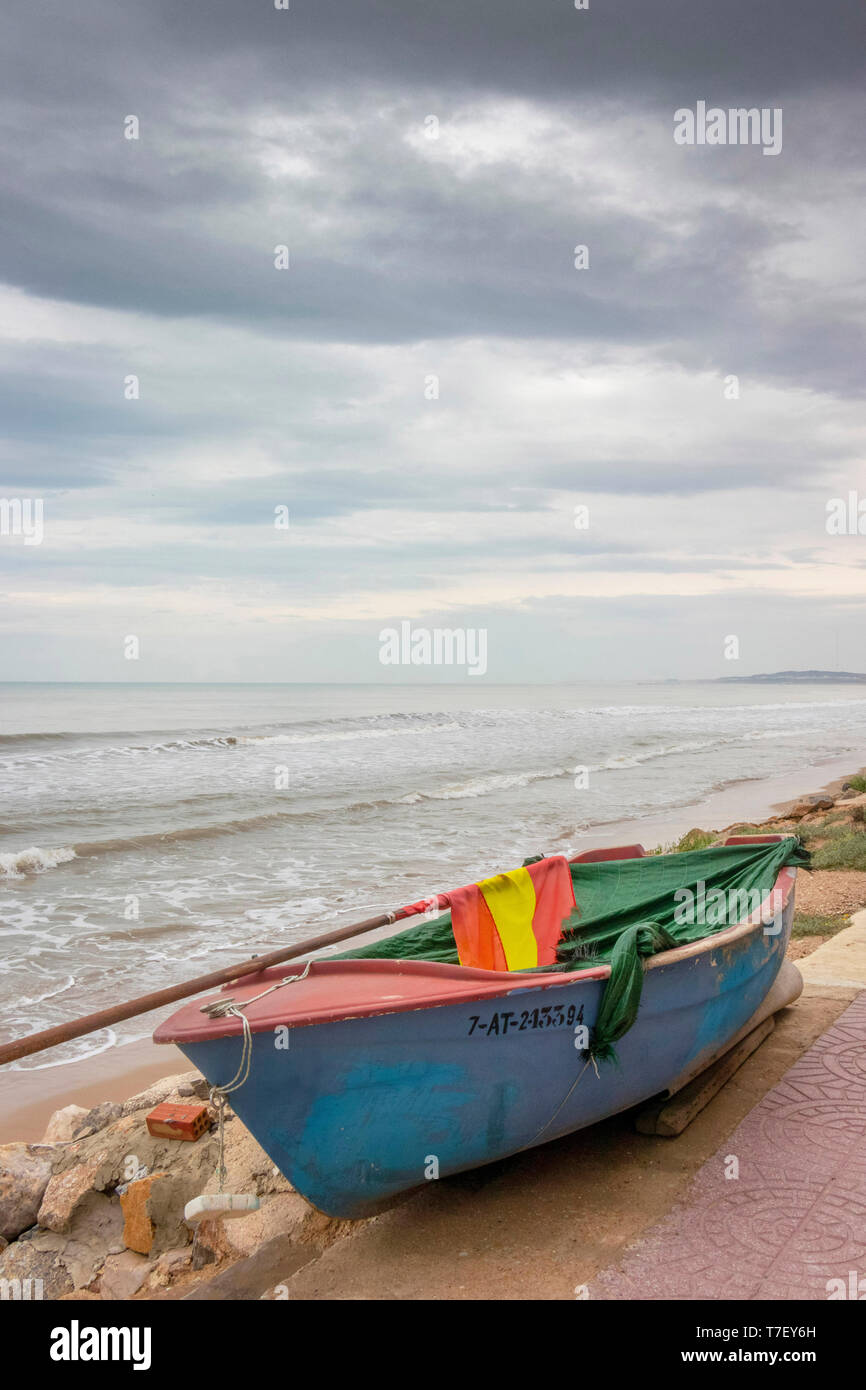Piccola barca da pesca in un giorno di tempesta di una spiaggia deserta a El Pinet, vicino a Elche Alicante in Spagna Foto Stock