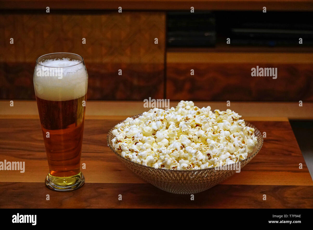 La pinta di birra ciotola di popcorn controller remoto e bicchieri su sfondo di legno intrattenimento casalinghi Foto Stock