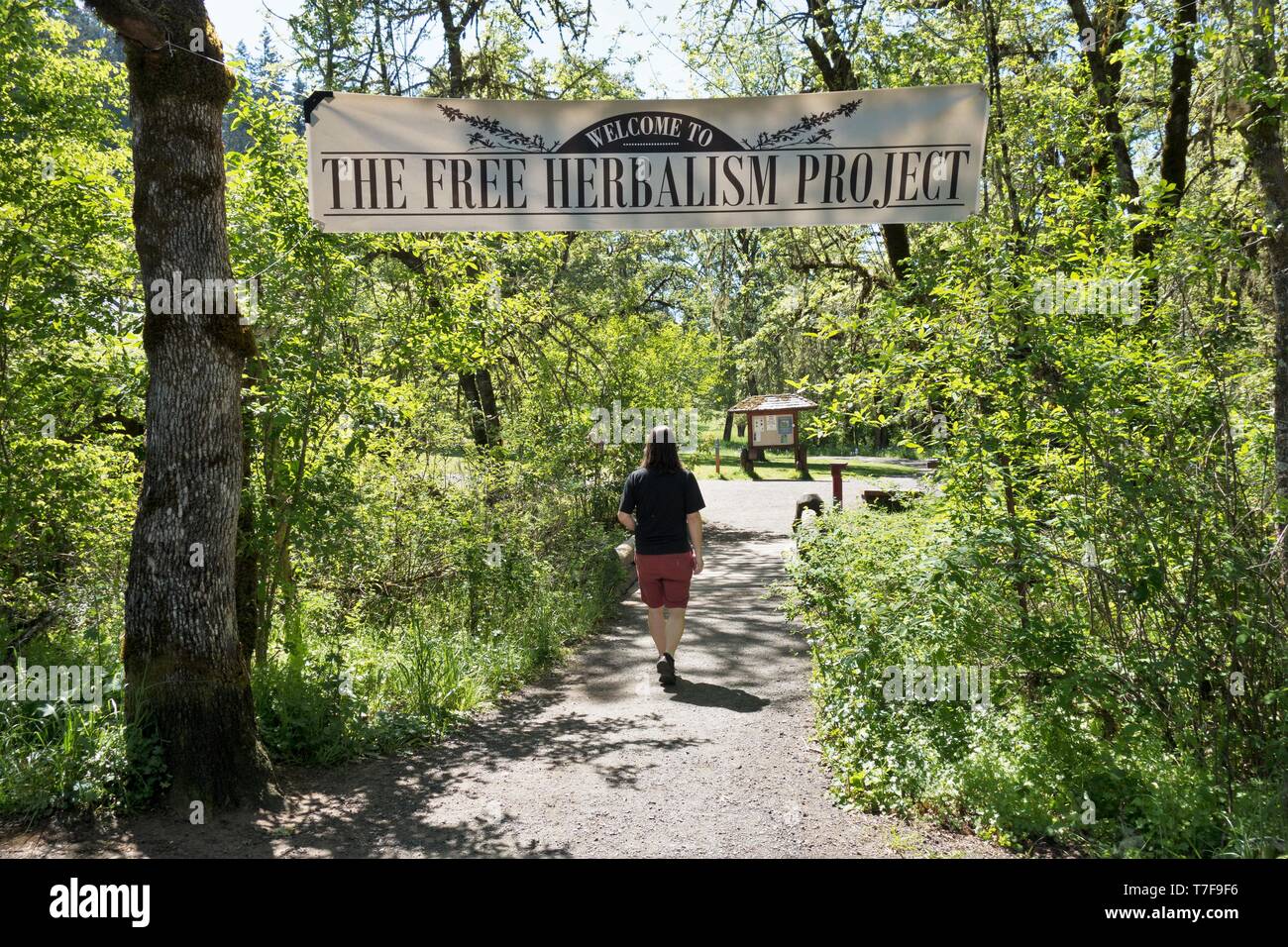 Una persona che cammina sotto un banner per la libera erboristeria progetto a Mount Pisgah Arboretum di Eugene, Oregon, Stati Uniti d'America. Foto Stock